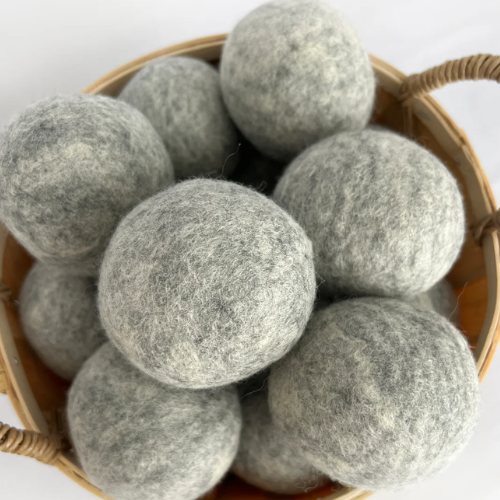Basket filled with gray wool dryer balls on a white background