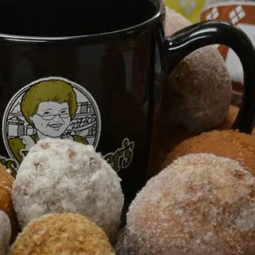 Black mug with a logo featuring a person and text, surrounded by donut holes.