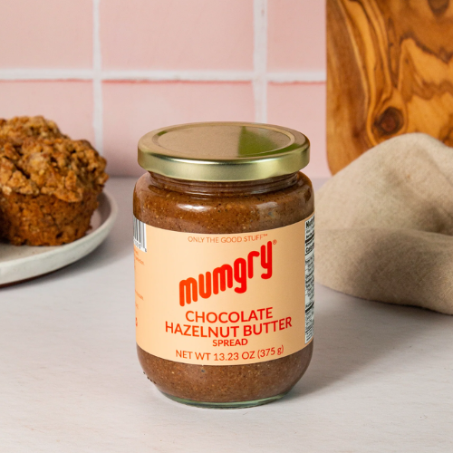 Jar of Mumgry Chocolate Hazelnut Butter on a table with a pink tiled wall in the background