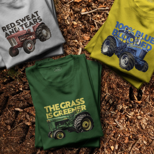 Three t-shirts with tractor graphics on a mulched surface