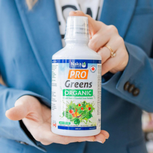 Person holding a bottle of Naka Pro Greens Organic supplement.