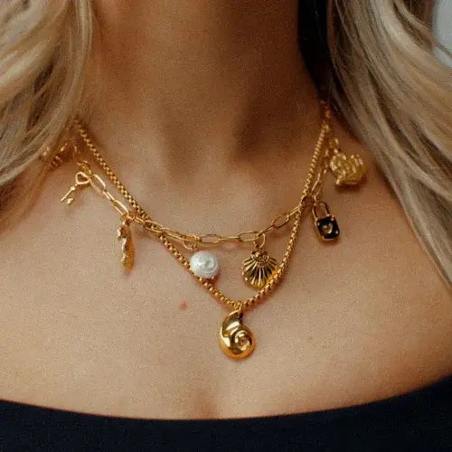 Layered gold charm necklaces with symbolic pendants including a shell, lock, and pearl – Handcrafted jewellery by Canadian-owned Namaste