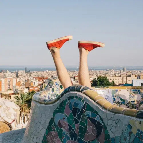 Person playfully posing with legs up wearing bright orange Native Shoes – Lightweight, vegan footwear by Canadian-owned Native Shoes