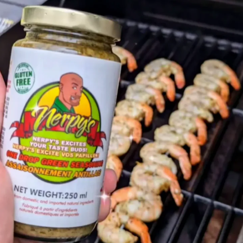 Jar of Nerpys seasoning held over grilled shrimp on a grill.