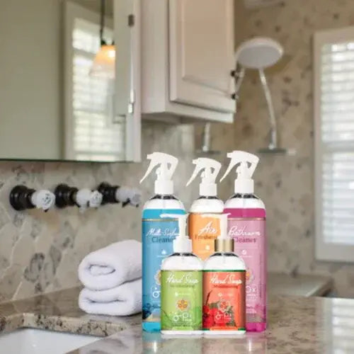 Bathroom cleaning products on a counter with towels and shower head in the background