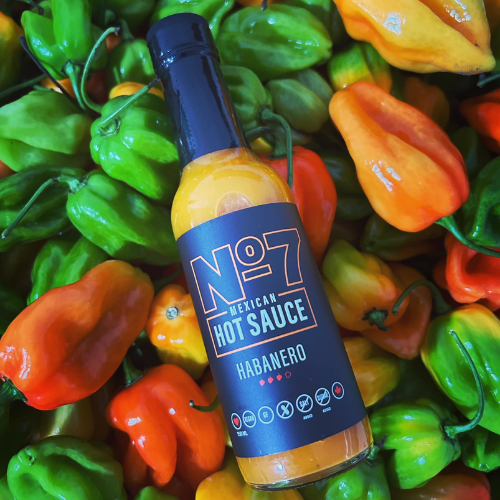 Bottle of No. 7 Mexican Hot Sauce Habanero surrounded by colourful habanero peppers.
