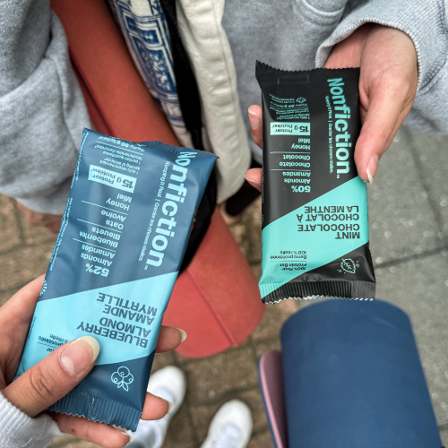 Two Nonfiction protein bars being held, one blue and one black and green.