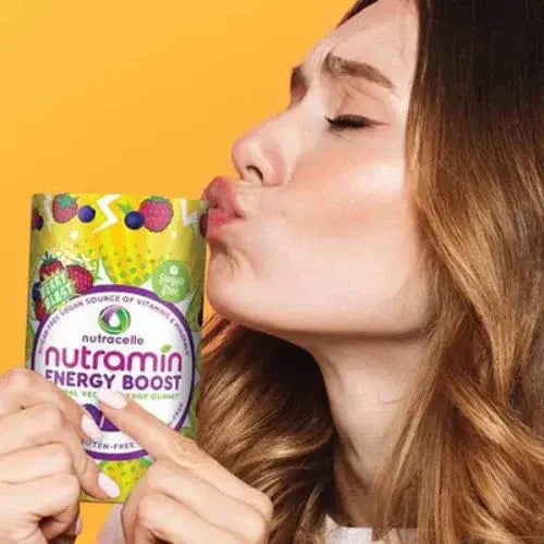Woman kissing a Nutramin Energy Boost container against a yellow background
