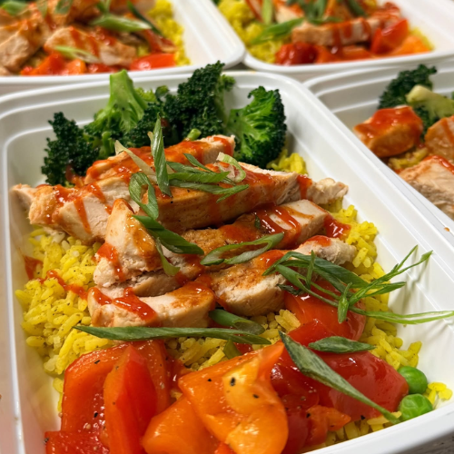 Plated Nutri-Go dish with chicken, rice, vegetables, and sauce in a white container.
