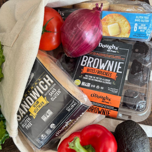 Gluten-free sandwich and brownie packages with vegetables on a table