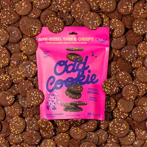 Pink package of 'Odd Cookie' cosmic brownies surrounded by cookies on a textured background
