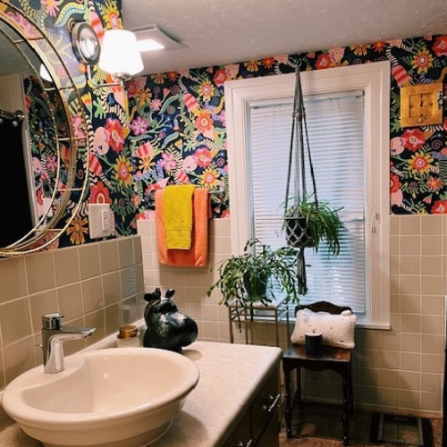 Bathroom with colorful floral wallpaper, sink, and window.