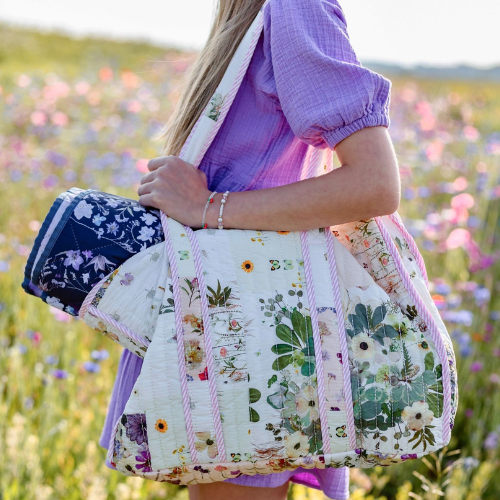 Person holding a floral quilt in a field of flowers