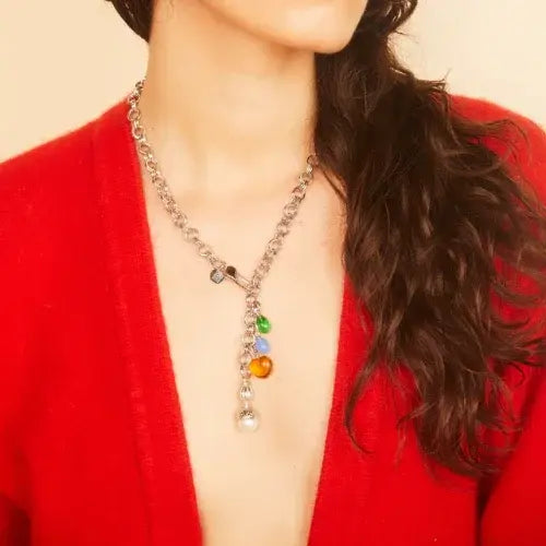 Necklace with colorful beads worn by a person in a red cardigan against a beige background