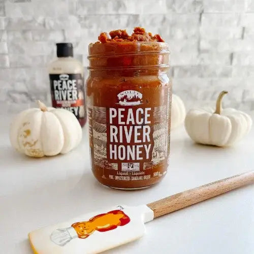 Jar of Peace River Honey with a spatula on a light background