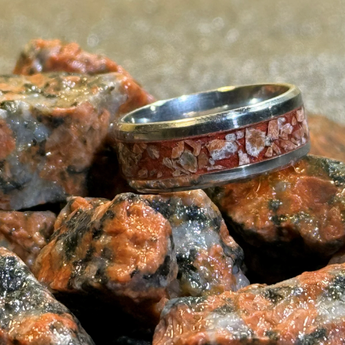 Silver ring with floral design on a pile of red and black stones