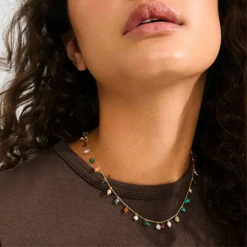 Close-up of a person wearing a delicate necklace with small beads.