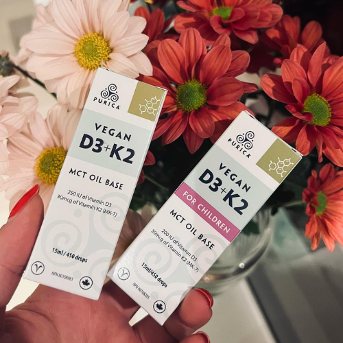 Two boxes of Purica Vegan D3+K2 MCT Oil Base with flowers in the background