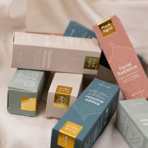 Collection of Puur Ingrid skincare product boxes on a light fabric background