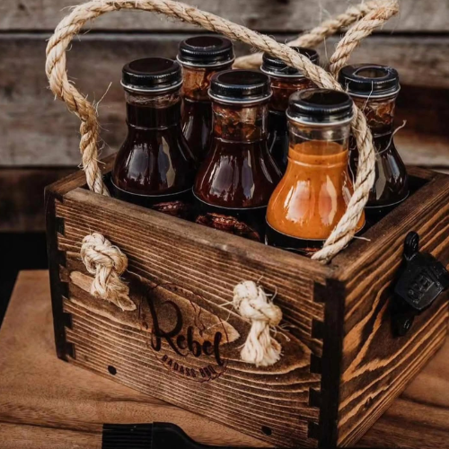 Wooden crate with bottles of rebel bbq sauce on a wooden surface