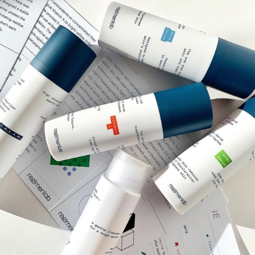 Multiple skincare products from the brand 'regimen lab' on a newspaper background