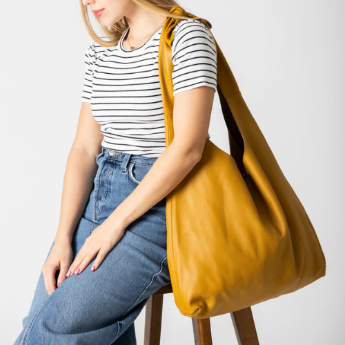 Woman holding a mustard yellow handbag against a white background