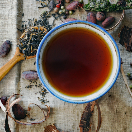 Tea cup with tea leaves and herbs on a textured surface