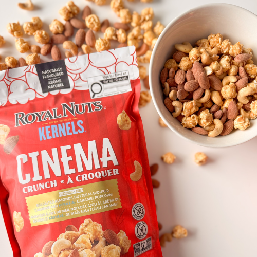 Bag of Royal Nuts Kernals Cinema Crunch with a bowl of mixed nuts and popcorn on a light background