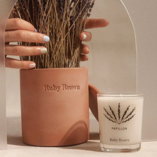 Terracotta pot with 'Ruby Brown' branding and a candle labeled 'Papillon' on a neutral background.