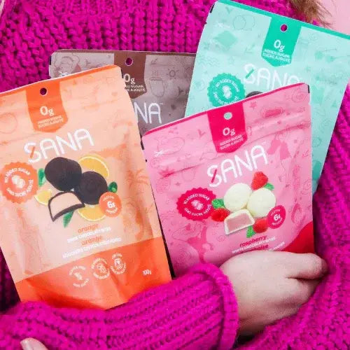 Sana candy packages in various flavors held by a person wearing a pink sweater.