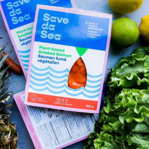 Two packages of 'Save da Sea' plant-based smoked salmon on a blue surface with greens and lemons.