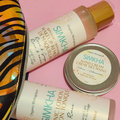 Simkha skincare products including a bottle, jar, and tube on a pink background