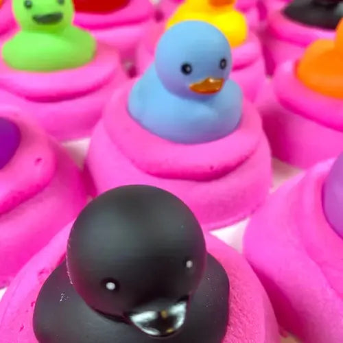 Colourful duck bath bombs with a focus on a black one, surrounded by other colourful ones