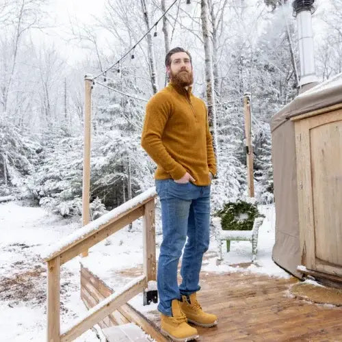 Man standing on a wooden deck by a hot tub in a snowy forest setting