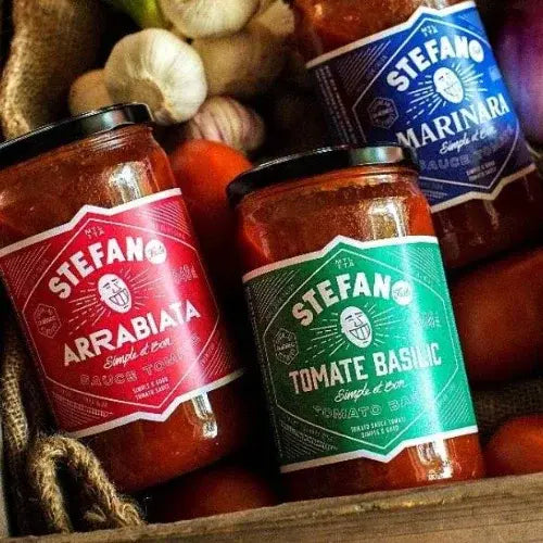 Three jars of Stefano brand tomato-based sauces with labels on a wooden surface.