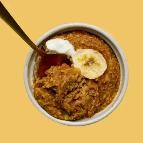 Mug cake with banana and whipped cream on a yellow background