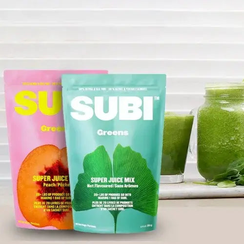 Two SUBI Greens packages with a glass of green juice on a white surface.