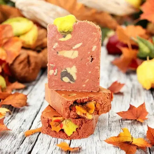 Stack of soap bars with autumn-themed decorations on a wooden surface with fall leaves.