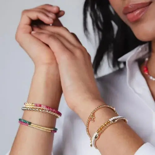 Close-up of a person wearing multiple bracelets on a plain background