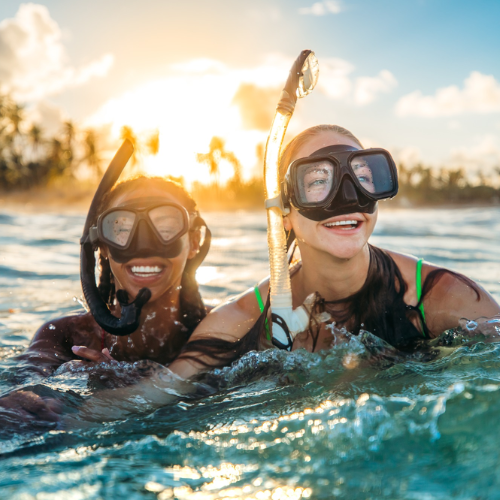 Two people snorkeling in the water with sunset in the background