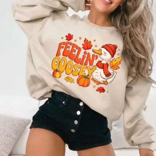 Person wearing a beige sweatshirt with 'Feelin' Goosey' graphic design.