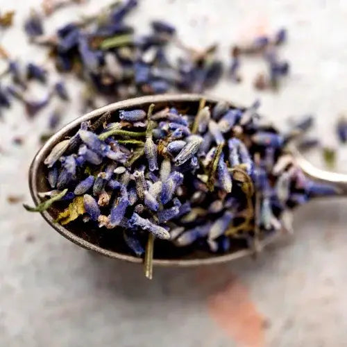Dried lavender flowers in a metal spoon on a marble surface