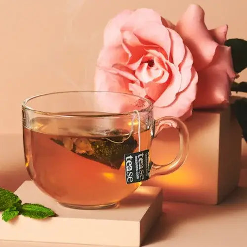 Clear glass mug with tea and a pink rose on a beige background