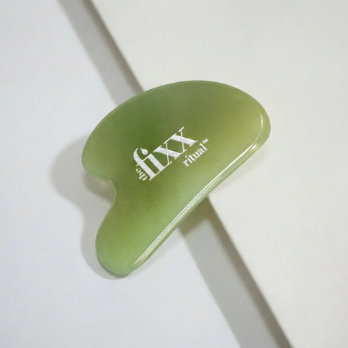 Green gua sha tool with 'the fixx ritual' branding on a white background