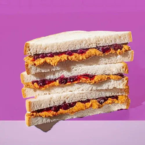 Stack of peanut butter and jelly sandwiches on a purple background