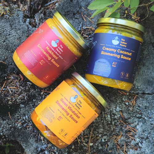 Three jars of different sauces on a textured surface with leaves.