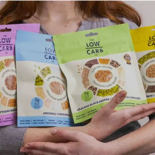 Person holding packages of 'The Low Carb Co' snacks