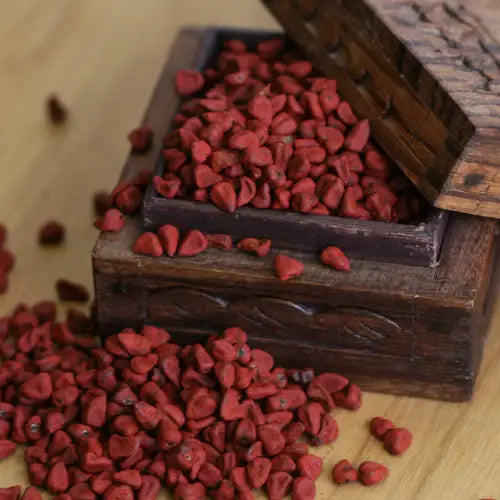 Wooden box with red annatto seeds on a wooden surface