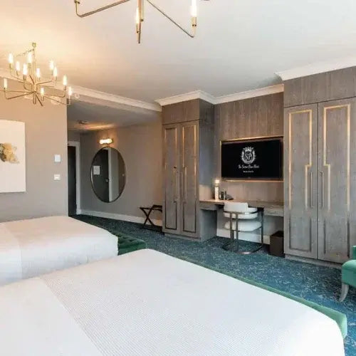 Modern hotel room with two beds, wardrobe, and television.