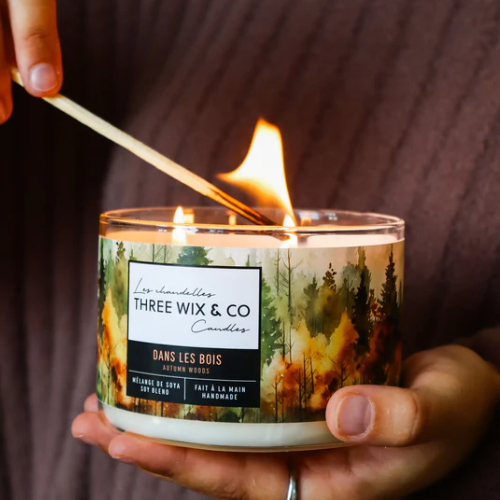 Candle being lit with a match, featuring 'Three Wix & Co' branding and forest design.